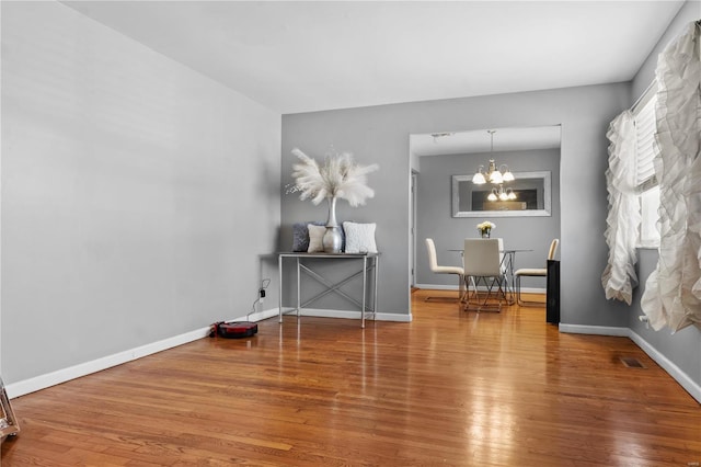 sitting room featuring baseboards, a notable chandelier, visible vents, and wood finished floors