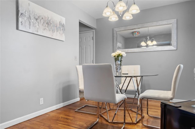 dining room featuring wood finished floors, baseboards, and an inviting chandelier