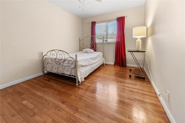 bedroom with ceiling fan, wood finished floors, and baseboards