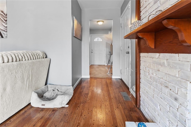 corridor featuring visible vents, hardwood / wood-style flooring, and baseboards