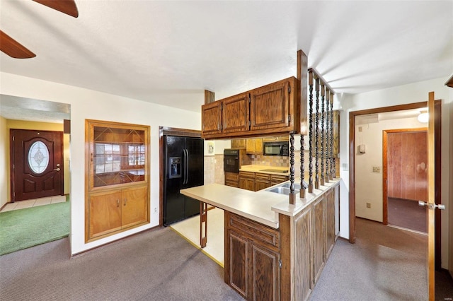 kitchen featuring kitchen peninsula, light colored carpet, and black appliances