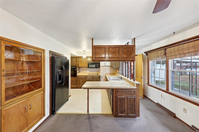 kitchen featuring sink, backsplash, hanging light fixtures, carpet, and black appliances