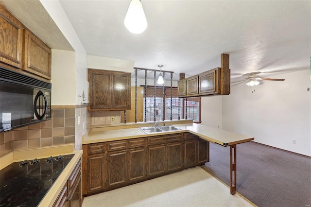 kitchen featuring pendant lighting, sink, black appliances, decorative backsplash, and kitchen peninsula