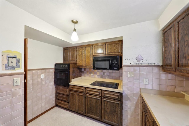 kitchen with pendant lighting, black appliances, and tile walls