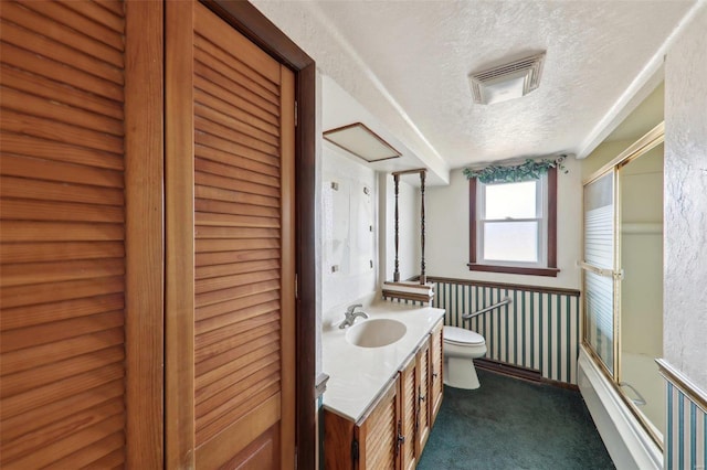 full bathroom featuring enclosed tub / shower combo, vanity, a textured ceiling, and toilet