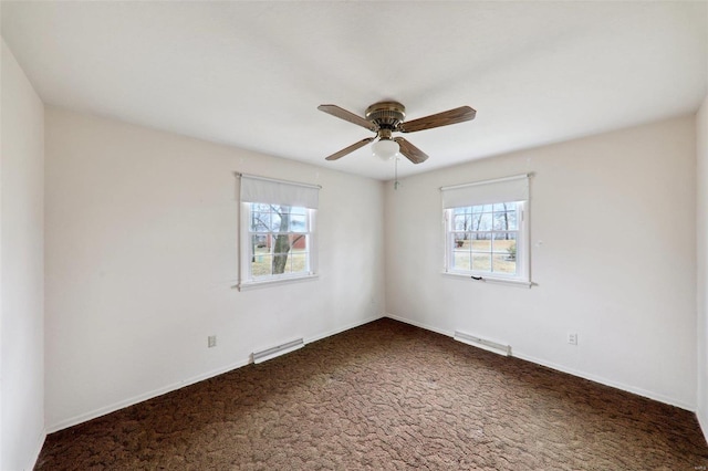 empty room with dark colored carpet, a healthy amount of sunlight, and ceiling fan