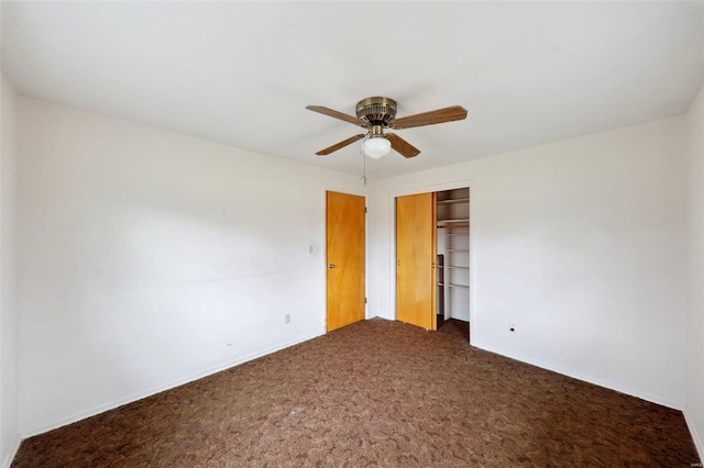 unfurnished bedroom with ceiling fan, dark carpet, and a closet