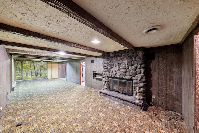 basement featuring wooden walls, a textured ceiling, and a fireplace