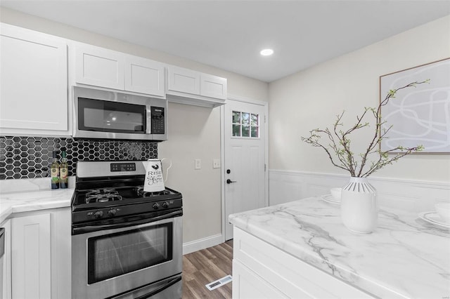 kitchen featuring light stone counters, white cabinetry, stainless steel appliances, and hardwood / wood-style flooring