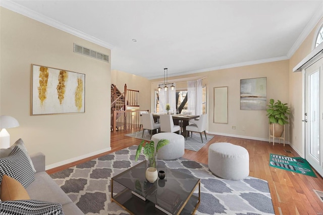 living room featuring an inviting chandelier, hardwood / wood-style flooring, and ornamental molding