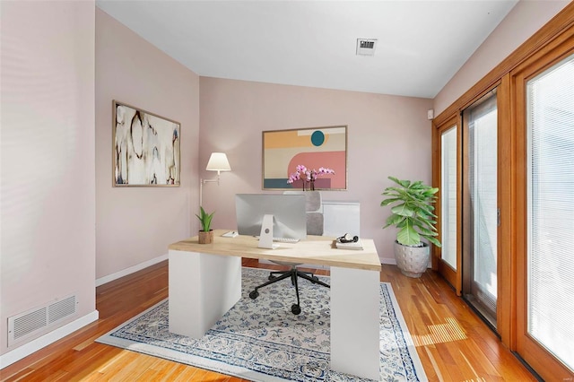 home office featuring lofted ceiling and light hardwood / wood-style flooring