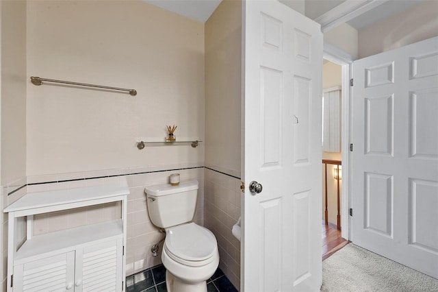 bathroom featuring tile walls, tile patterned floors, and toilet