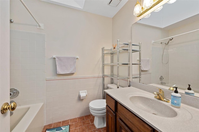 full bathroom with tile walls, tile patterned flooring, vanity, tiled shower / bath combo, and toilet