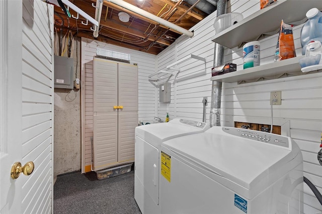 clothes washing area with washer and dryer, electric panel, and wooden walls