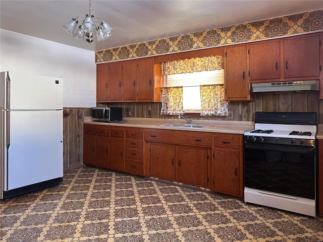 kitchen with sink, gas stove, an inviting chandelier, decorative light fixtures, and white fridge