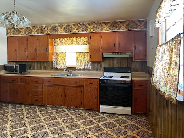 kitchen with sink, gas range, hanging light fixtures, and a chandelier