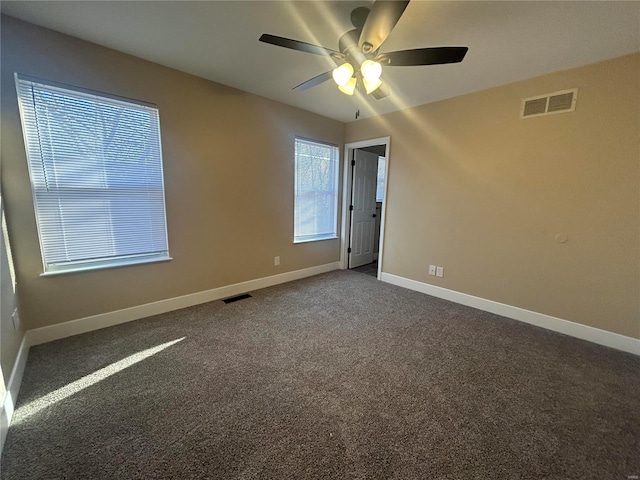 spare room with dark carpet and ceiling fan