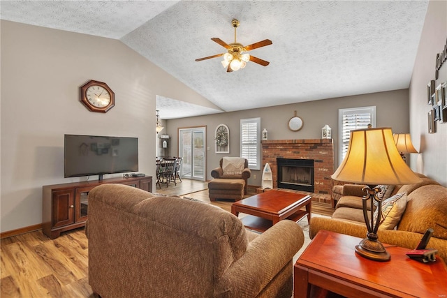 living room featuring a healthy amount of sunlight, lofted ceiling, a textured ceiling, and light hardwood / wood-style flooring