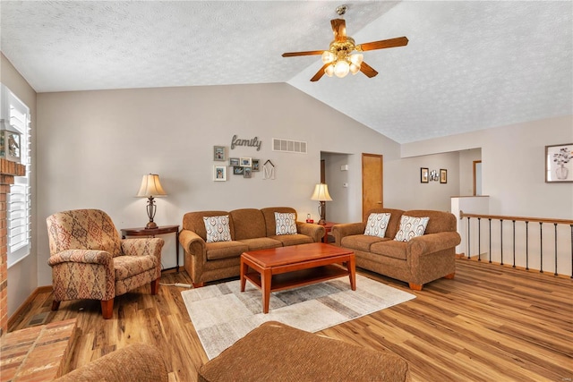 living room featuring ceiling fan, lofted ceiling, light hardwood / wood-style floors, and a textured ceiling