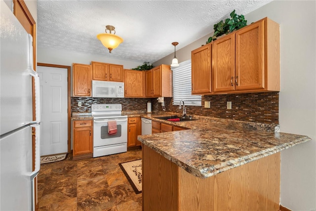 kitchen with hanging light fixtures, sink, white appliances, and kitchen peninsula