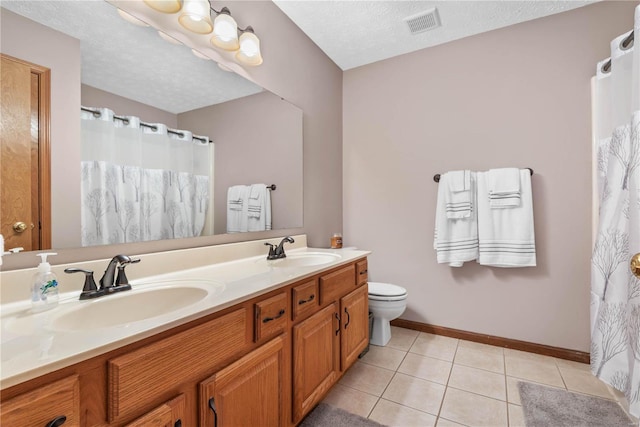 bathroom with tile patterned flooring, vanity, a textured ceiling, and toilet