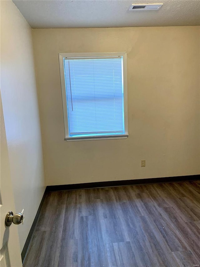 spare room with dark hardwood / wood-style flooring and a textured ceiling