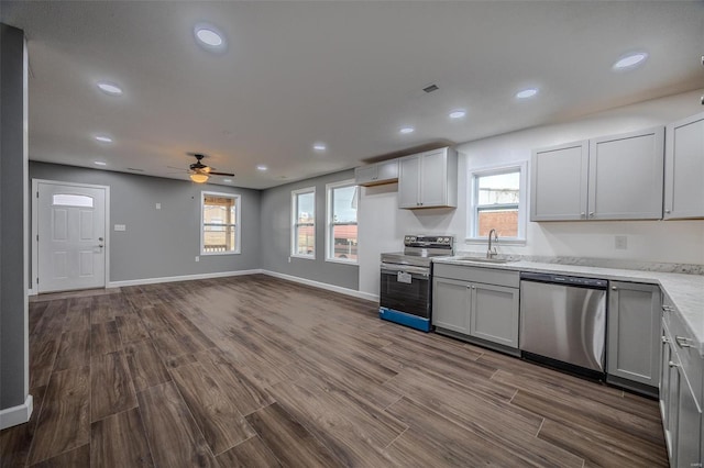 kitchen featuring dark wood-type flooring, sink, gray cabinetry, ceiling fan, and stainless steel appliances