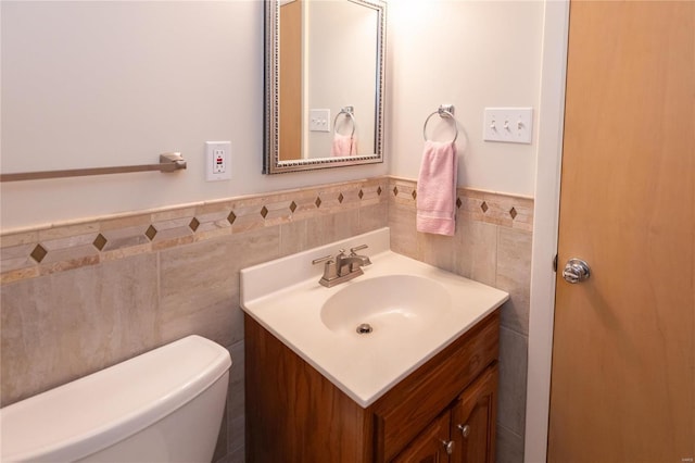 bathroom featuring vanity, toilet, and tile walls