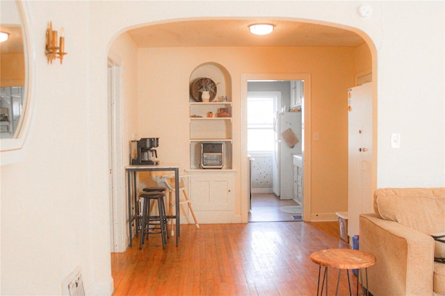 hall with hardwood / wood-style floors and built in shelves