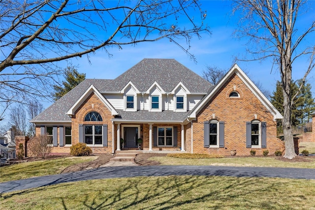 traditional home with brick siding, a front lawn, and a shingled roof