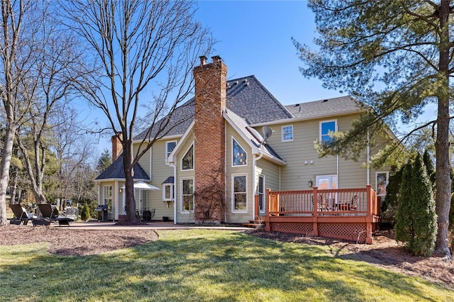 rear view of house featuring a deck, a lawn, and a chimney