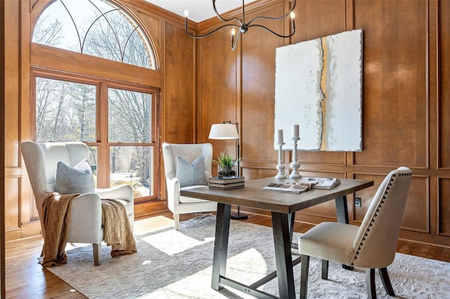 interior space with a notable chandelier, wood finished floors, and a decorative wall