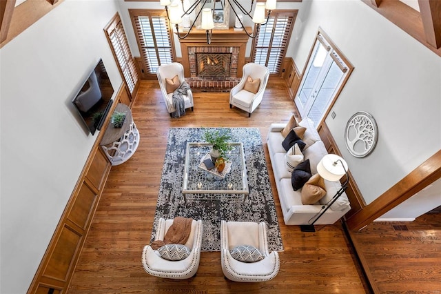 living area with a healthy amount of sunlight, a fireplace, a chandelier, and wood finished floors