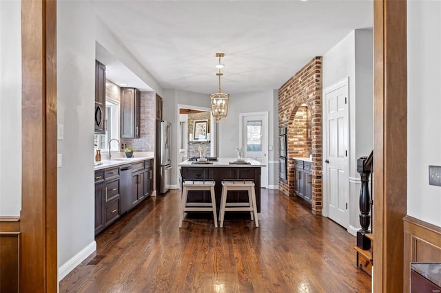 interior space featuring dark wood-style floors, a kitchen island, stainless steel appliances, a kitchen bar, and a sink