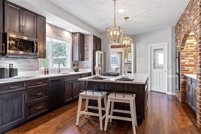 kitchen with a sink, dark brown cabinetry, stainless steel appliances, and dark wood finished floors