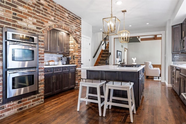 kitchen with dark wood-style floors, dark brown cabinets, stainless steel appliances, and light countertops