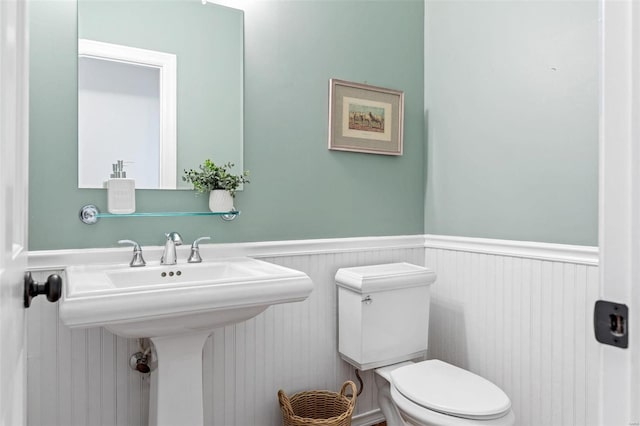 bathroom with toilet, a sink, and wainscoting