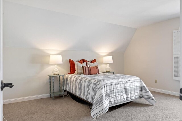 bedroom with vaulted ceiling, carpet flooring, and baseboards