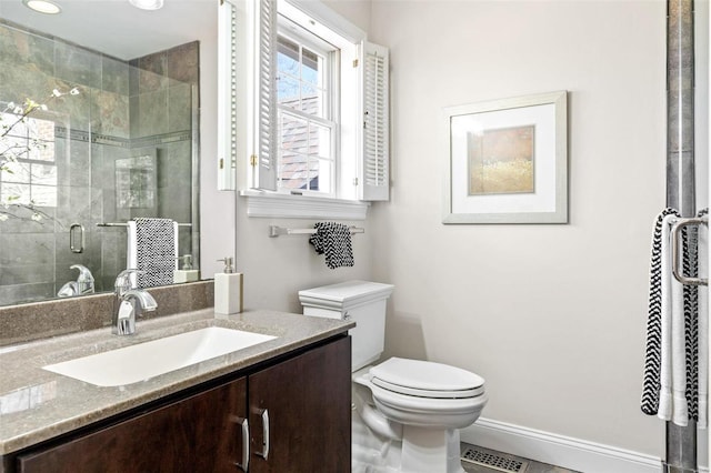 full bath with visible vents, toilet, a shower stall, vanity, and baseboards