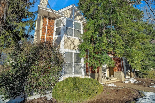 view of property exterior featuring a chimney and brick siding