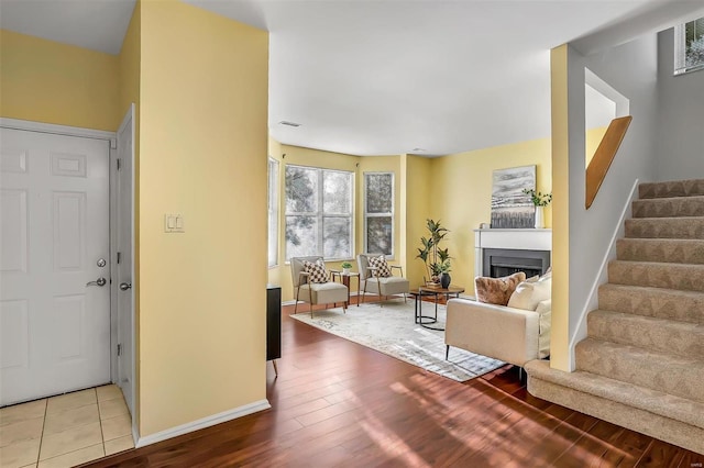 foyer featuring stairs, a fireplace, wood finished floors, and baseboards