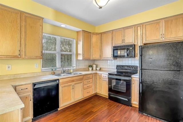 kitchen with dark wood finished floors, light countertops, light brown cabinetry, a sink, and black appliances