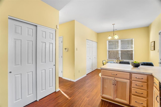 kitchen featuring hanging light fixtures, baseboards, light countertops, and dark wood-style flooring