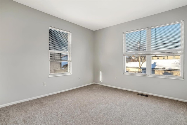 carpeted empty room featuring visible vents and baseboards
