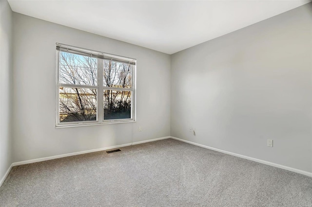 spare room featuring carpet floors, visible vents, and baseboards
