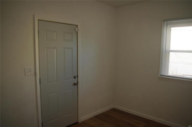 spare room featuring dark wood-type flooring and plenty of natural light