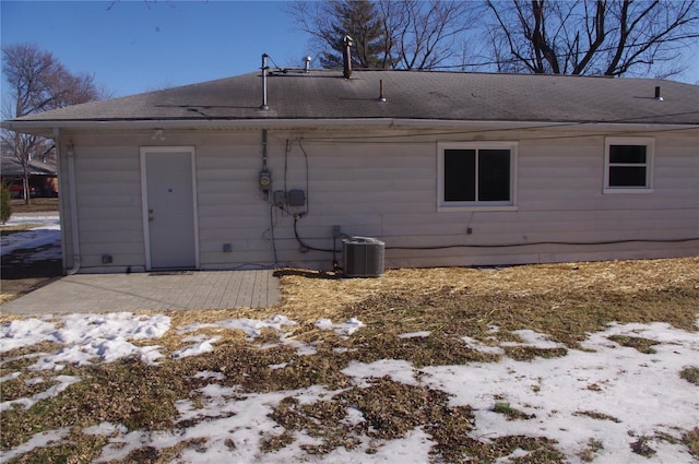 snow covered rear of property featuring a patio and central air condition unit