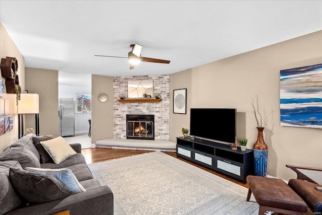 living room featuring wood-type flooring, ceiling fan, and a fireplace