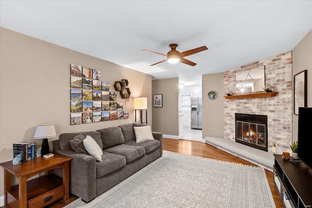 living room with ceiling fan, wood-type flooring, and a fireplace