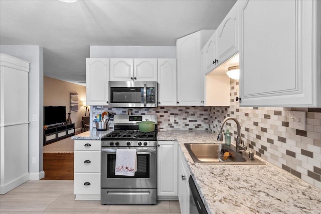 kitchen with white cabinetry, sink, backsplash, and stainless steel appliances